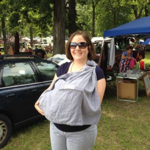 Mom outdoors wearing the baby in a sling carrier