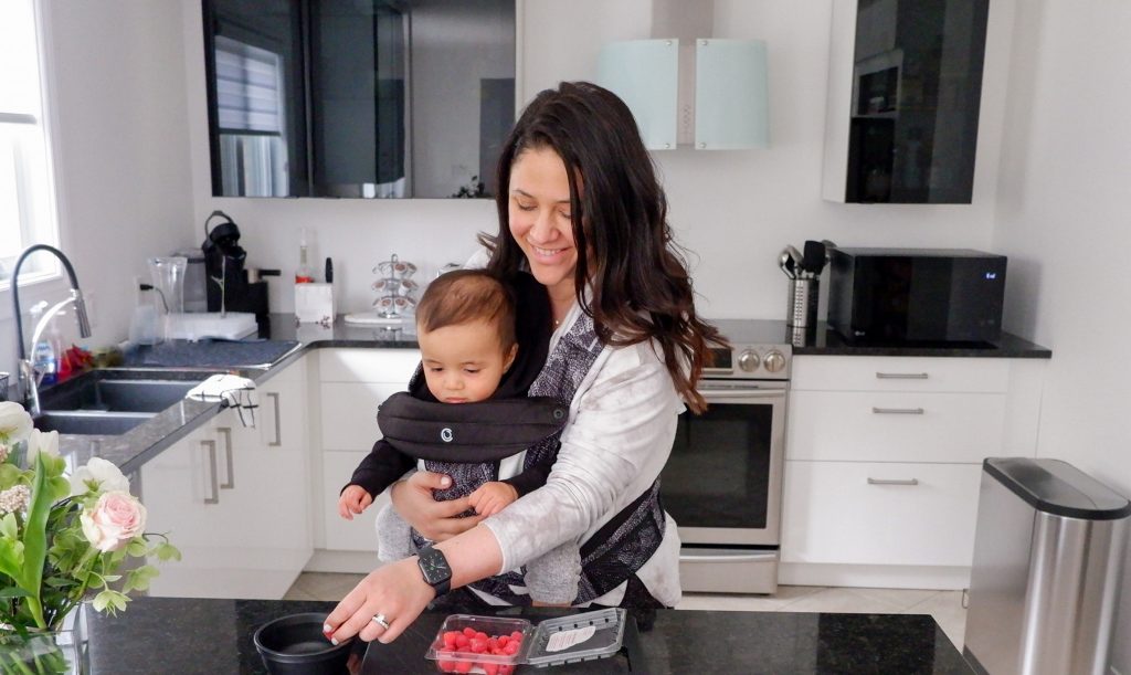 Mom in the kitchen wearing baby in the Cocoon carrier